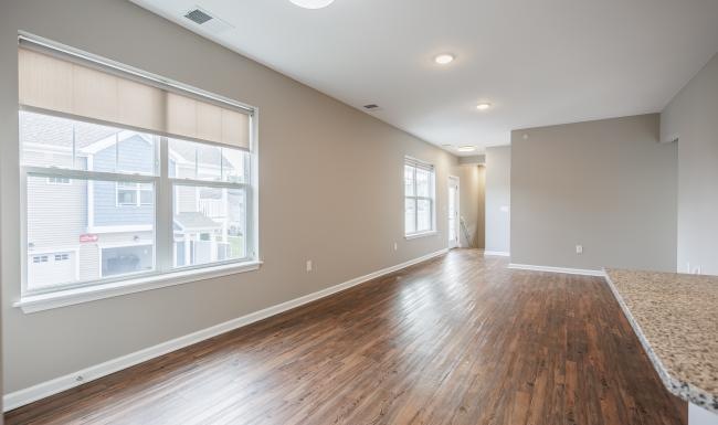 a large empty room with a wood floor and a large window